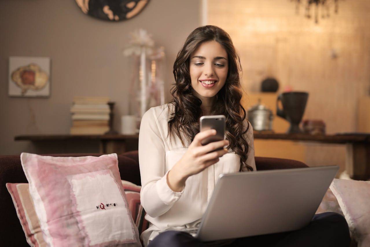 Person sitting with laptop and throw pillow, talking on a smartphone, looking concerned, surrounded by gadgets and clothing with A text nearby.